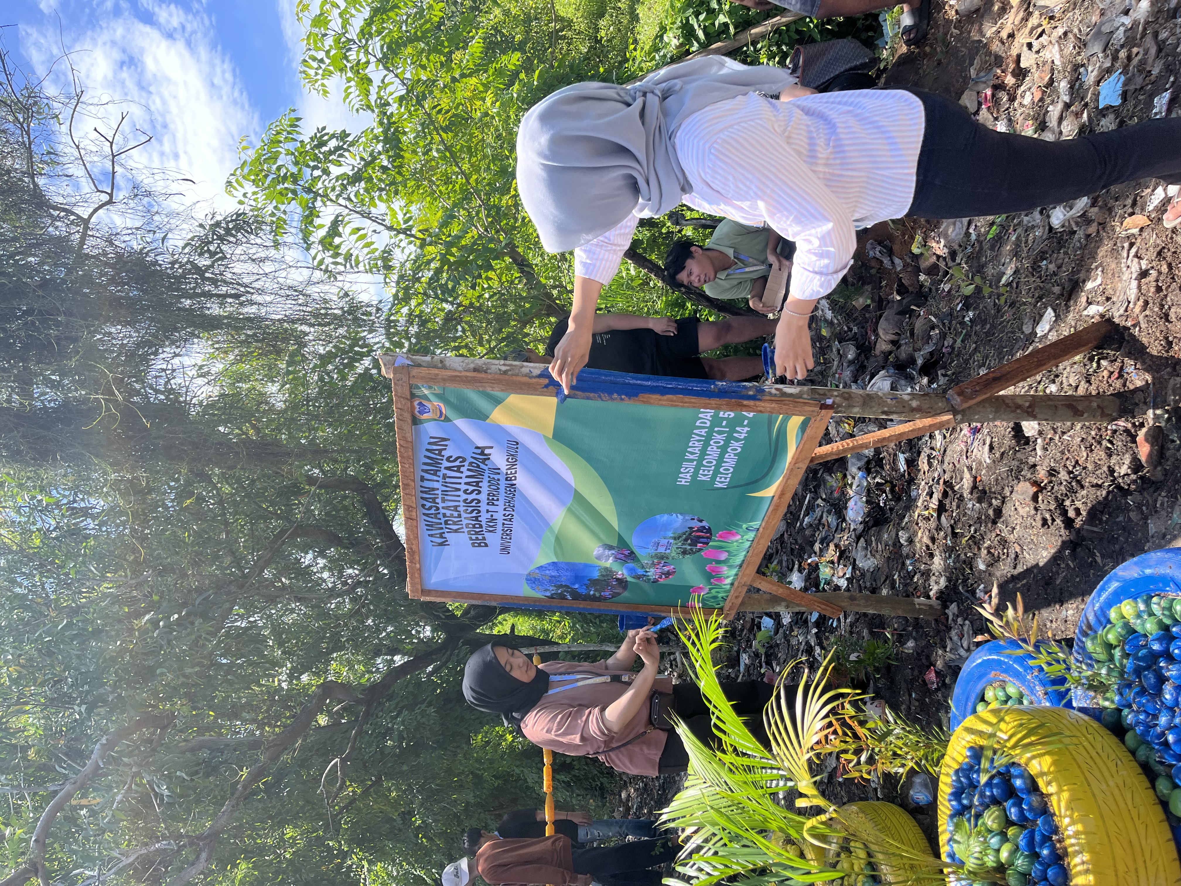 Proses mengecat tiang spanduk di taman