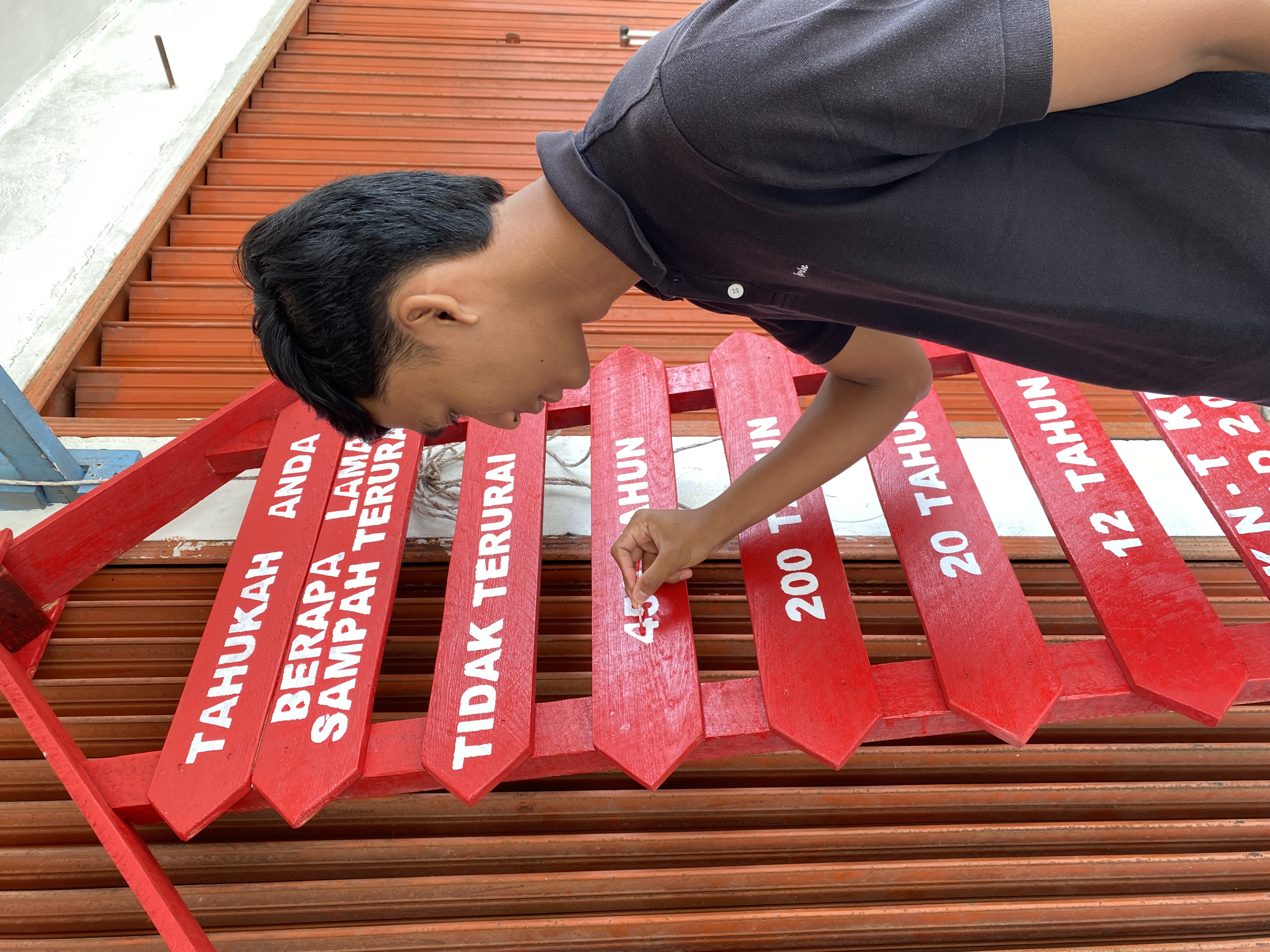 Merapikan tulisan di papan edukasi sampah