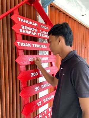 Merapikan tulisan di papan edukasi sampah